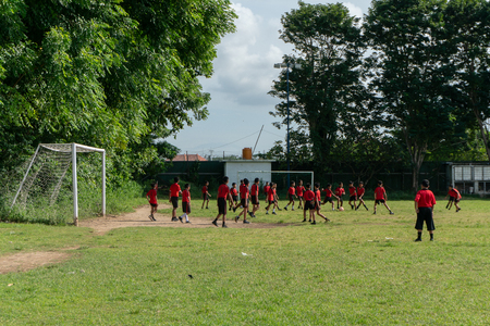 BADUNG,BALI/INDONESIA-APRIL 05 2019: Elementary student in Bali play football or soccer on the field with red jersey.のeditorial素材