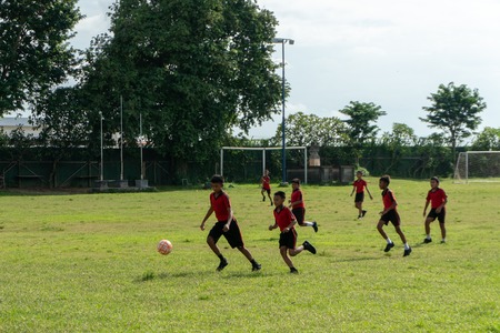 BADUNG,BALI/INDONESIA-APRIL 05 2019: Elementary student in Bali play football or soccer on the field with red jersey.のeditorial素材