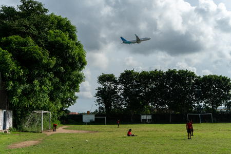 BADUNG,BALI/INDONESIA-APRIL 05 2019: Elementary student in Bali play football or soccer on the field near the airport with red jersey.のeditorial素材