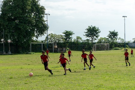 BADUNG,BALI/INDONESIA-APRIL 05 2019: Elementary student in Bali play football or soccer on the field with red jersey.のeditorial素材