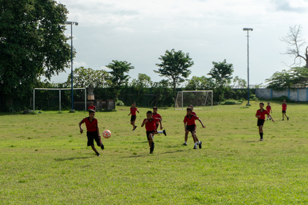 BADUNG,BALI/INDONESIA-APRIL 05 2019: Elementary student in Bali play football or soccer on the field with red jersey.のeditorial素材
