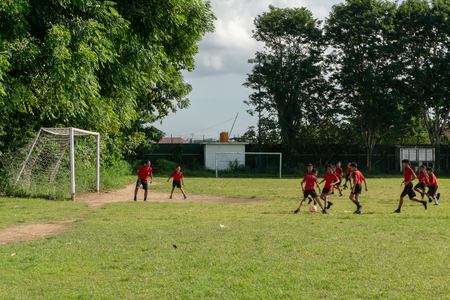 BADUNG,BALI/INDONESIA-APRIL 05 2019: Elementary student in Bali play football or soccer on the field with red jersey.のeditorial素材