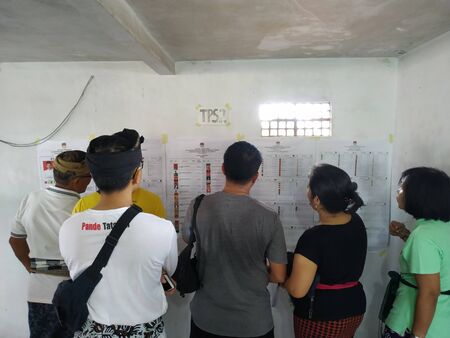 BALI/INDONESIA-APRIL 17 2019: Balinese people vote for the president and parliament 2019. They go to the polling stations using traditional clothes. Some people seen sample ballot papers before voting itのeditorial素材