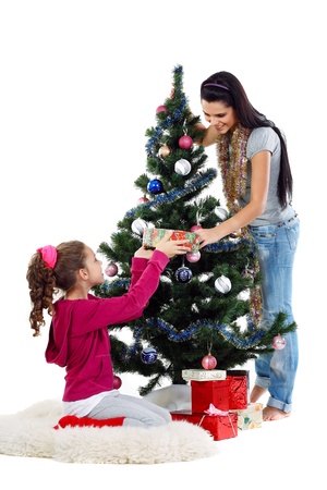 Mother and daughter near a christmas tree with gifts, isolated on a white backgroundの写真素材