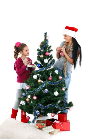 Mother and daughter near a christmas tree with gifts, isolated on a white backgroundの写真素材