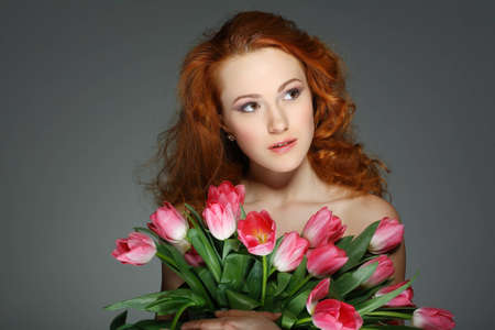 beautiful young redheaded girl with tulipsの写真素材