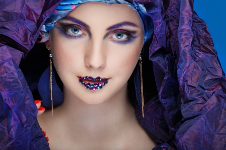 A photo of beautiful  girl in a head-dress from the coloured fabric,on a blue background  glamourの写真素材