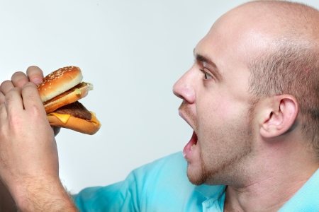 Funny man eating hamburger on grey backgroundの写真素材
