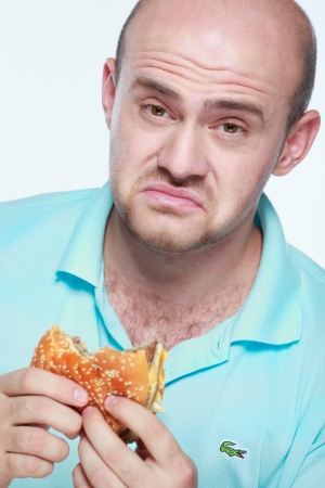 Funny man eating hamburger on grey backgroundの写真素材