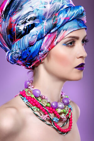 A photo of beautiful  girl in a head-dress from the coloured fabric,on a violet background  glamourの写真素材