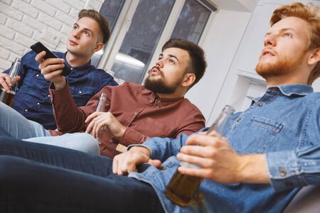 Men watching sport on tv together at home american football close-up