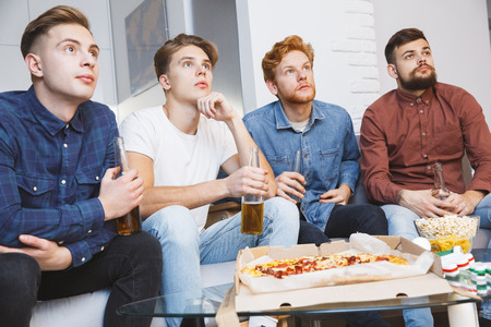 Men watching sport on tv together at home concentratedの写真素材