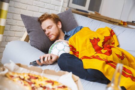 Man watching sport on tv at home alone sleepingの写真素材