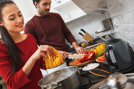 Young couple having romantic evening at home in the kitchen cooking meal togetherの写真素材