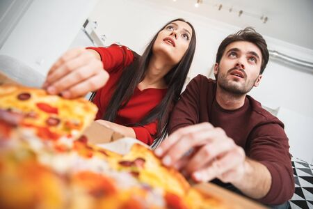 Young couple having romantic evening at home eating pizza close-upの写真素材