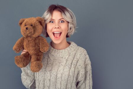 Young woman in a woolen sweater isolated on grey wall winter concept playingの写真素材
