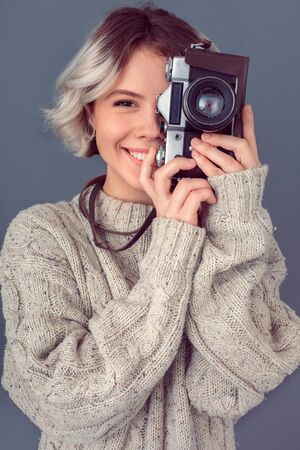 Young woman in a woolen sweater isolated on grey wall winter concept taking picturesの写真素材