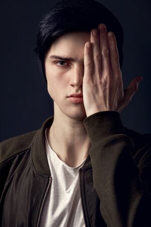 Young man isolated on a grey wall studio concept cover faceの写真素材