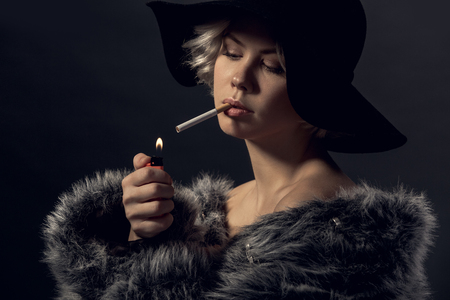 Young woman luxury style isolated on grey wall smokerの写真素材
