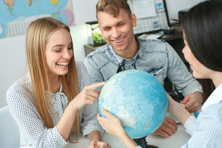 Young couple in a tour agency communication with a travel agent travelling concept choosing destinationの写真素材
