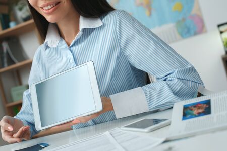 Young female travel agent consultant in tour agency showing online serviceの写真素材