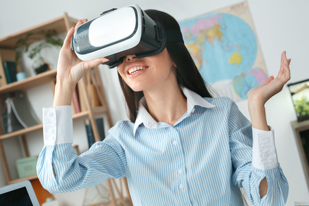 Young female travel agent consultant in tour agency playing virtual reality headset