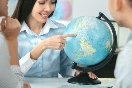 Young couple in a tour agency communication with a travel agent travelling concept globe choosing countryの写真素材