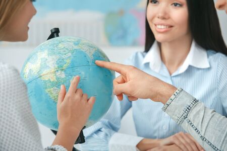 Young couple in a tour agency communication with a travel agent travelling concept globe choosing destination close-upの写真素材