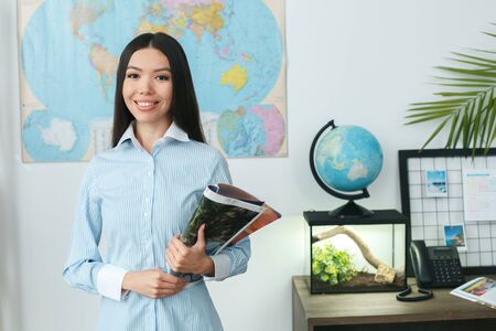 Young female travel agent consultant in tour agency standing looking cameraの写真素材