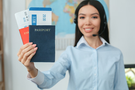 Young female travel agent consultant in tour agency holding documentsの写真素材
