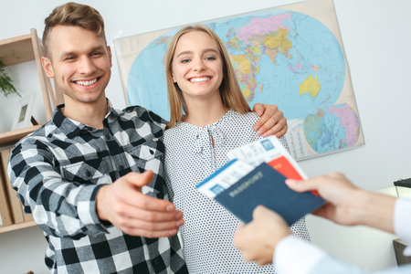 Young couple in a tour agency communication with a travel agent travelling concept taking documentsの写真素材