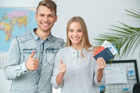 Young couple in a tour agency travelling concept holding documents thumbs upの写真素材