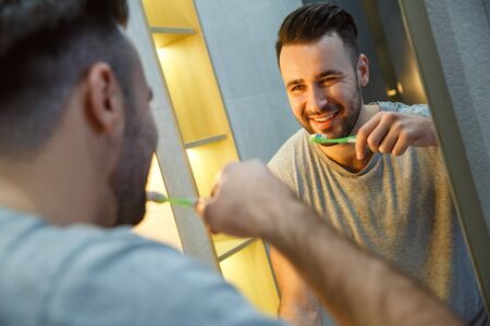 Bachelor man daily routine in a bathroom single lifestyle concept teeth cleaning mirror reflectionの写真素材