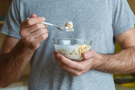 Bachelor man daily routine in a kitchen single lifestyle concept muesli with yoghurt close-upの写真素材
