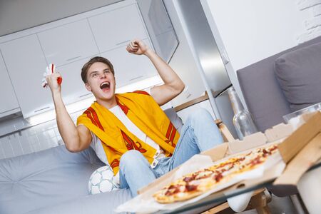 Man watching sport on tv at home alone cheeringの写真素材