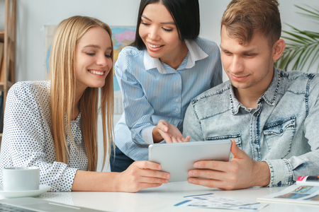 Young couple in a tour agency communication with a travel agent travelling concept digital tablet online serviceの写真素材