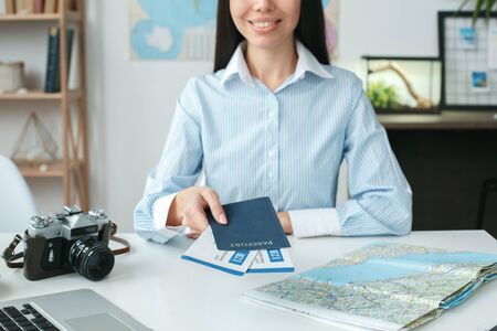 Young female travel agent consultant in tour agency holding documentsの写真素材
