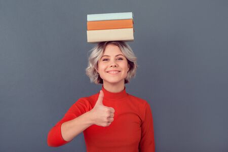 Young woman in a red blouse isolated on grey wall books