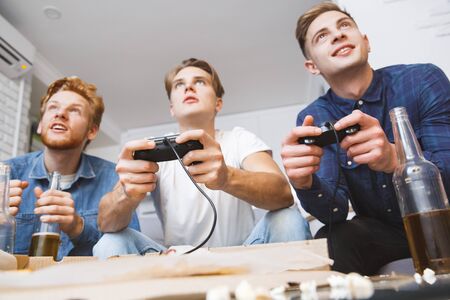Men playing football on game console together at homeの写真素材