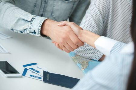 Young couple in a tour agency communication with a travel agent travelling concept handshakeの写真素材