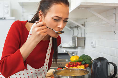 Young woman cooking romantic dinner at home taste soupの写真素材