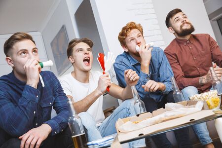 Men watching sport on tv together at home team spirit cheeringの写真素材