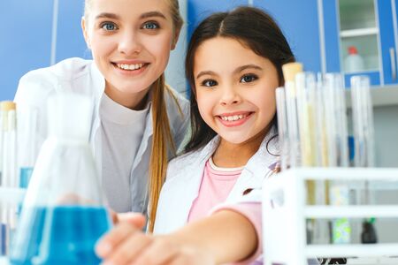 Teacher with little child in school laboratory bulb with liquidの写真素材