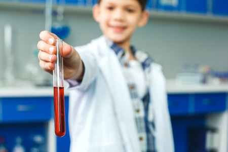 Little child with learning class in school laboratory holding vialの写真素材