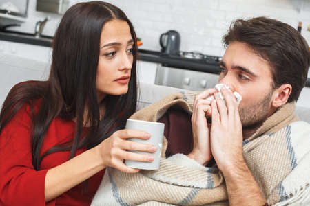 Young couple having evening at home girlfriend taking careの写真素材