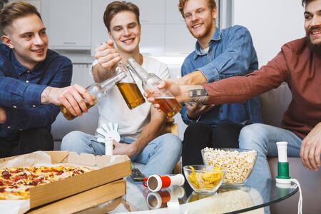 Men watching sport on tv together at home cheers for winの写真素材