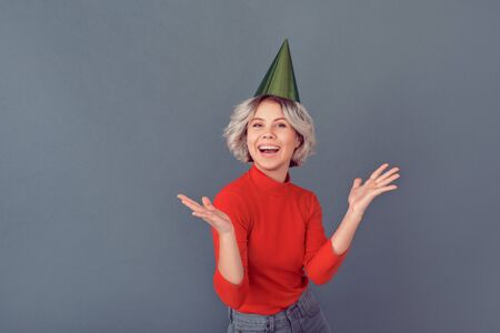 Young woman in a red blouse isolated on grey wall partyの写真素材