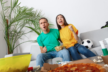 Young couple sport fans watching match shouting cheeringの写真素材