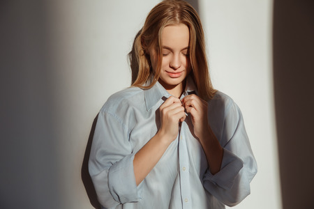Young woman at home isolated morning light shadows concept looking downの写真素材