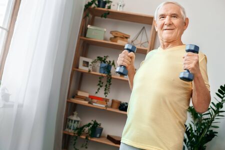Senior man exercise at home health care with dumbbells smilingの写真素材